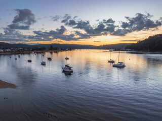 Fototapeta premium Aerial sunrise waterscape with boats and scattered clouds