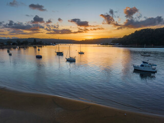 Fototapeta premium Aerial sunrise waterscape with boats and scattered clouds