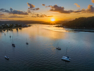 Fototapeta premium Aerial sunrise waterscape with boats and scattered clouds