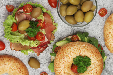 Fototapeta na wymiar Sesame bagels with tomatoes, ham and olives 