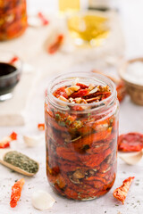Sun dried tomatoes on white bowl, white wooden background. Dried tomatoes with olive oil, salt, herbs and garlic recipe. Top view, copyspace.