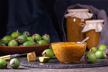Feijoa jam in a glass bowl with cut green feijoa fruits. Natural homemade dessert. Rural still-life closeup with selective focus