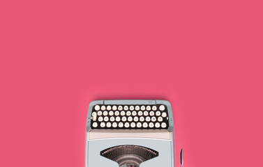 Overhead top view of a vintage aqua blue typewriter against a pink background