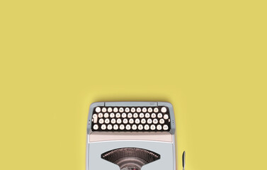 Overhead top view of a vintage aqua blue typewriter against a yellow background