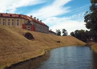 Protective moat with water around a medieval castle in Eastern Europe. Protective walls of a medieval fortress with a water channel around. Water around the castle.