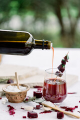  Beet kvass in a glass and mason jar with loose beets, side view, gray background