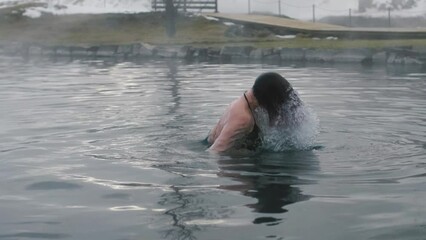woman relaxing in geothermal spa on Iceland. Woman enjoying bathing in a blue lagoon Icelandic tourist attraction. 