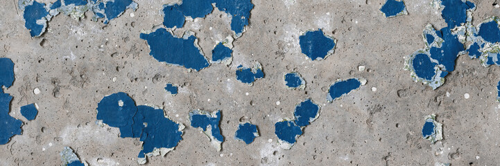Peeling paint on the wall. Panorama of a concrete wall with old cracked flaking paint. Weathered rough painted surface with patterns of cracks and peeling. Panoramic texture for background and design.