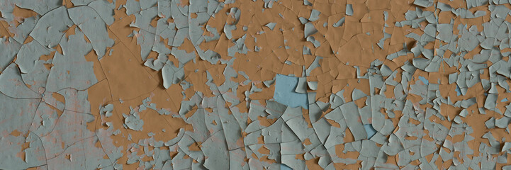 Peeling paint on the wall. Panorama of a concrete wall with old cracked flaking paint. Weathered rough painted surface with patterns of cracks and peeling. Wide panoramic grungy texture for background