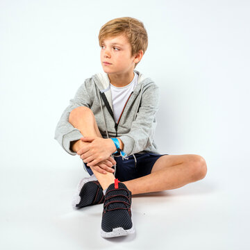 Handsome young boy sitting with legs crossed looking to the side