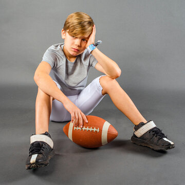 Male youth football player sitting and crying after losing a game