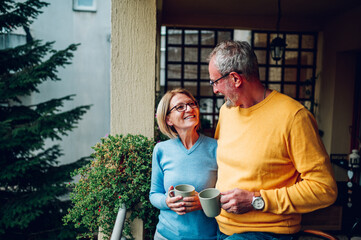 Senior couple drinking coffee or tea at balcony or terrace at home