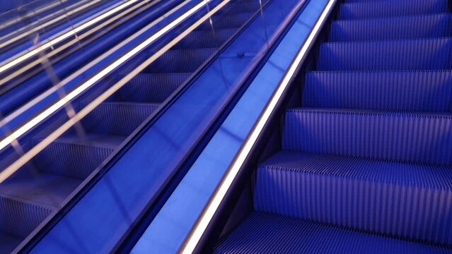 Selective focus view of moving up escalator under blue light atmosphere. 