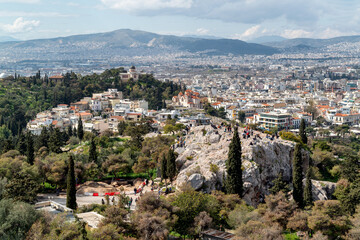 Fototapeta na wymiar Panoramic view to Athens as seen from the Acropolis. People at the Areopagus Hill enjoying the view to Athens, the old National Observatory ontop the Nymphs hill