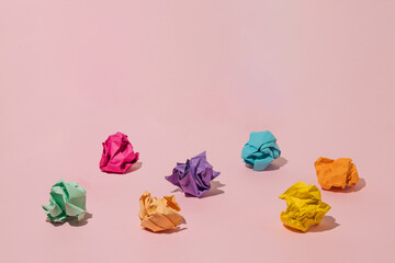 Colorful crumpled paper balls on pink background.