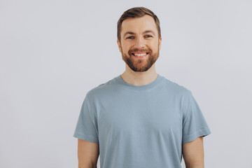 Fototapeta premium Portrait of a modern bearded middle-aged man in a blue t-shirt showing emotions on a white background