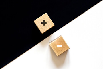 White of plus and black minus sign in opposite side and color of wooden cube background. Black and white. Choice concept.