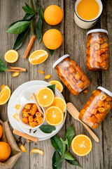 Homemade candied peels orange syrup in glass jar , on the background of sliced oranges