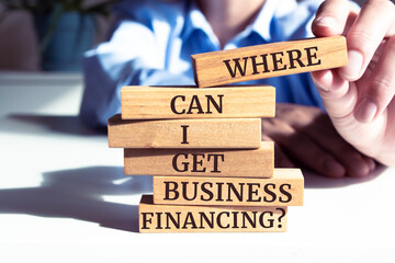 Close up on businessman holding a wooden block with "Where Can I Get Business Financing?" message