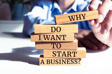 Close up on businessman holding a wooden block with "Why Do I Want to Start a Business?" message