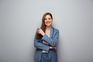 Smiling business woman in suit pointing finger up. Isolated female portrait.