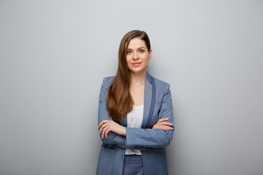 Smiling woman in business suit standing with crossed arms, female portrait.