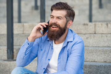 man smile has smartphone call outside. man has smartphone call in the street.