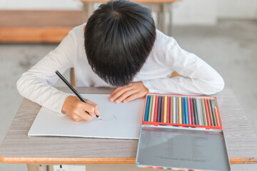 学校の図工の授業・お絵かき教室・習い事で色鉛筆を使って絵を描く小学生の男の子
