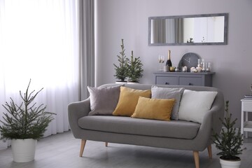 Beautiful room interior with decorated Christmas firs and comfortable sofa