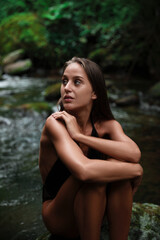 Obraz premium Beautiful young woman sitting on rock near mountain river outdoors