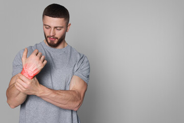 Arthritis symptoms. Man suffering from pain in his wrist on light grey background, space for text