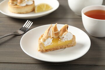 Piece of delicious lemon meringue pie on wooden table