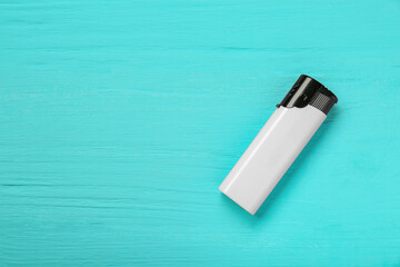 Stylish small pocket lighter on turquoise wooden background, top view. Space for text