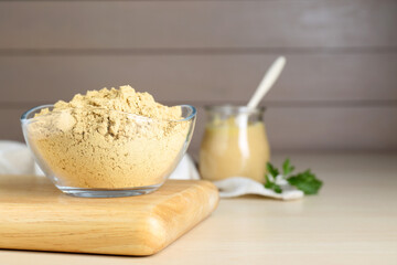 Bowl of aromatic mustard powder on wooden table. Space for text