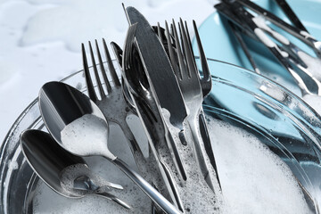 Glass bowl with silverware in foam, closeup