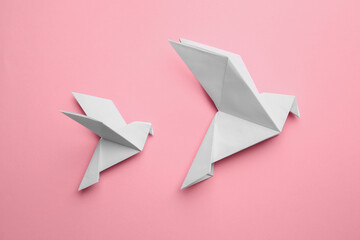 Beautiful origami birds on pink background, flat lay