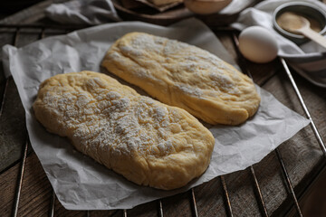 Raw dough for ciabatta and flour on wooden table