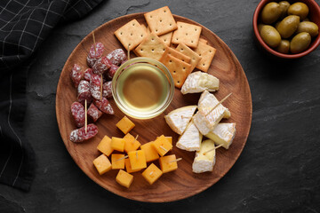 Toothpick appetizers. Pieces of cheese, sausage and honey on black table, flat lay