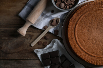 Delicious homemade sponge cake and different kinds of chocolate on wooden table, flat lay