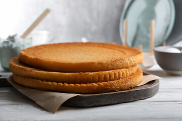 Delicious homemade sponge cakes and ingredients on white wooden table, closeup