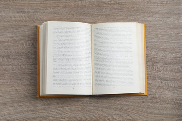 Obraz premium Open hardcover book on wooden table, top view
