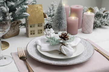 Festive place setting with beautiful dishware, cutlery and cone for Christmas dinner on white wooden table