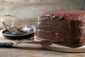 Delicious homemade layer cake with chocolate cream on wooden table, closeup