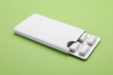 Blister with chewing gums on pale green background, closeup