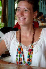 Close up of a wooden necklace worn by a cheerful young woman sitting in a cool restaurant in Puerto Viejo, Costa Rica.