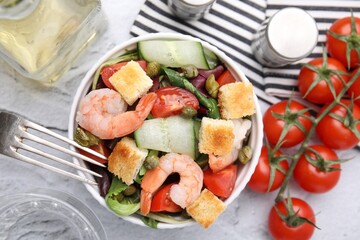 Tasty salad with croutons, tomato and capers on white textured table, flat lay