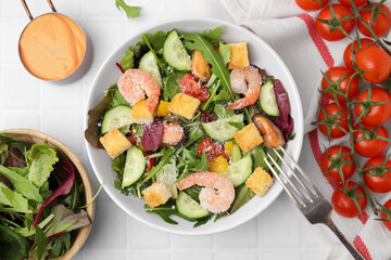Delicious salad with croutons, cucumber and shrimp served on white tiled table, flat lay