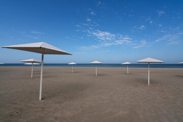 A deserted beach with wooden umbrellas on the shore of the Baltic Sea in the village of Yantarny, Kaliningrad region, Russia