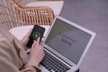 Woman unlocking smartphone with fingerprint scanner, closeup. Her laptop password protected to