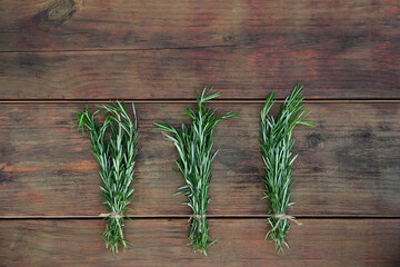 Bunches of fresh rosemary on wooden table, flat lay. Aromatic herb